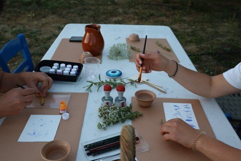 Eine Gruppe von Menschen malt draußen an einem Tisch mit Malutensilien. 4