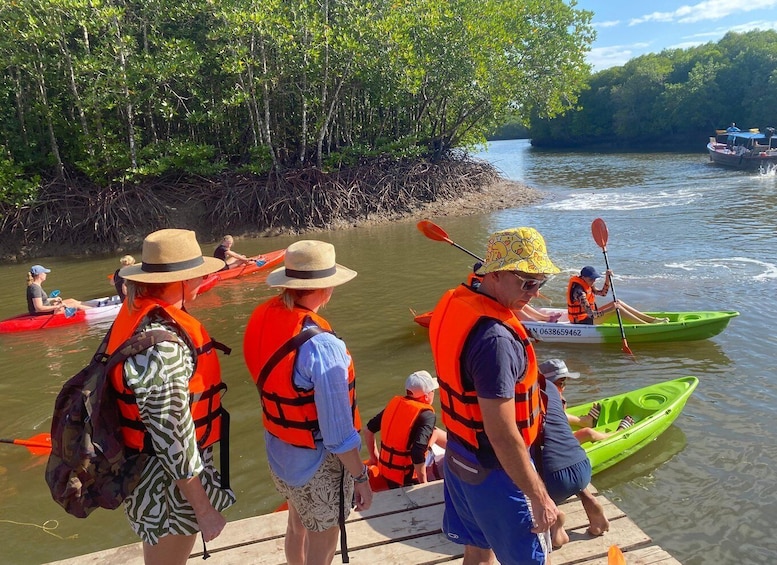 People in kayaks and life vests on a riverbank, preparing to paddle. 5