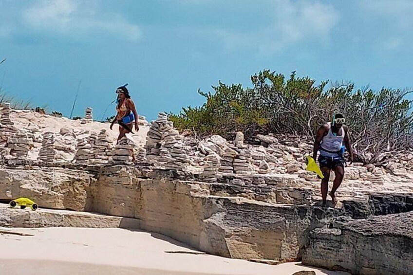 Two people walking on a rocky beach with a clear sky. 3