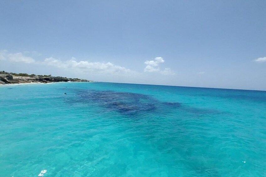 Clear turquoise ocean water, a sandy beach, and a rocky coastline. 4