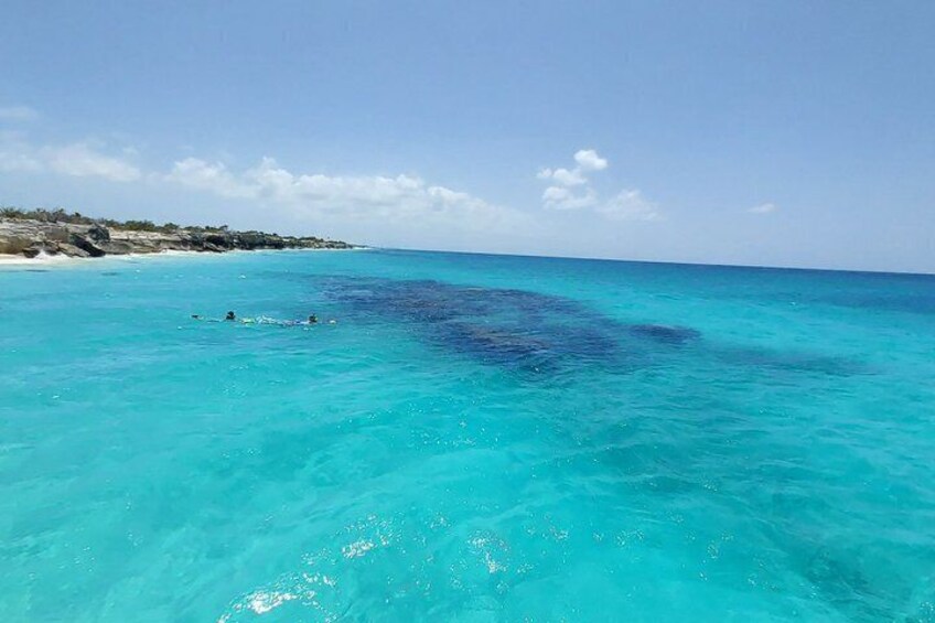 Clear turquoise waters, a sandy beach, and a distant rocky coastline. 5
