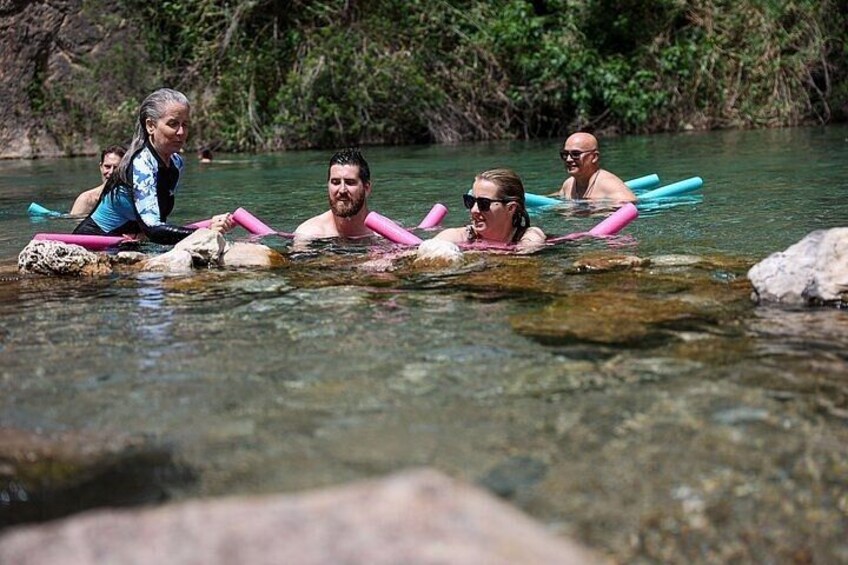 Personas flotando en un río, con rocas y vegetación al fondo. 3