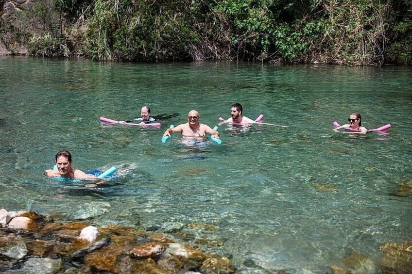 Personas flotando en un río de aguas cristalinas y rocas visibles. 2