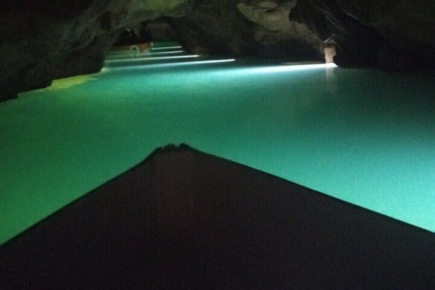 Una cueva con un sendero iluminado en verde y una estructura de madera. 3