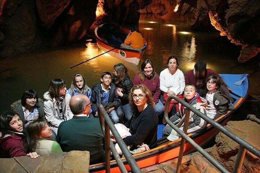 Un grupo de personas en un bote, dentro de una cueva con paredes rocosas y agua. 5
