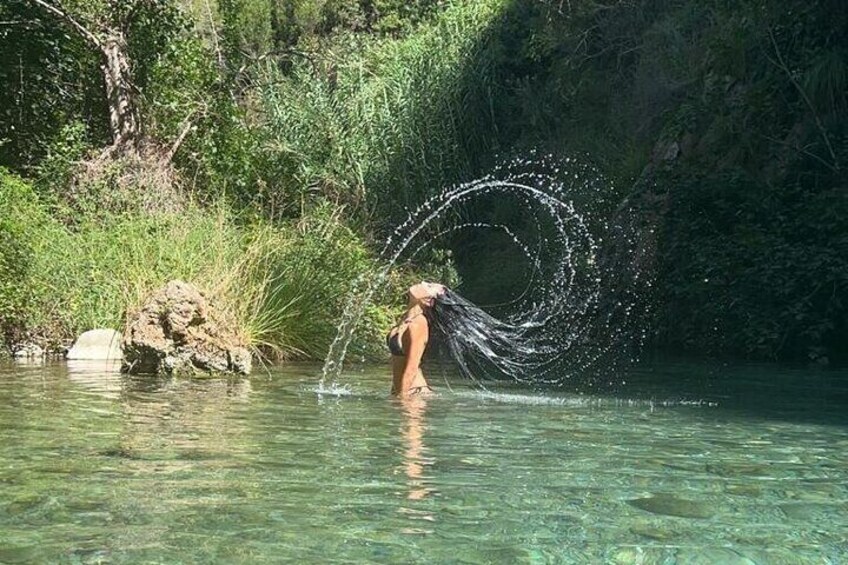 A person in a natural water body surrounded by greenery. 1