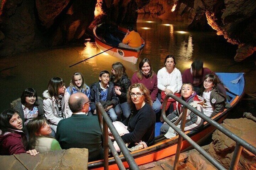 A group of people in a boat inside a cave with rocky walls. 5