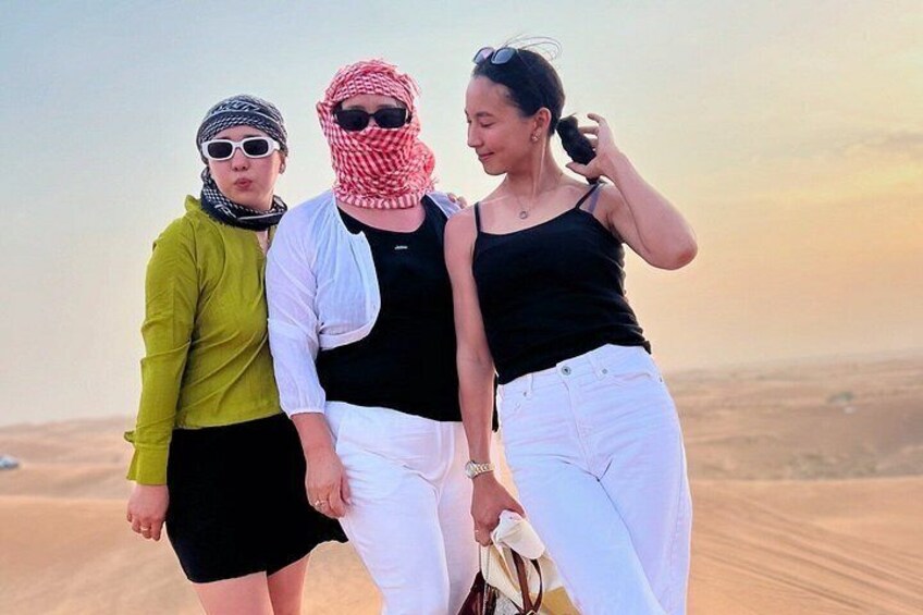 Three people standing on a sandy terrain with a desert landscape in the background. 5