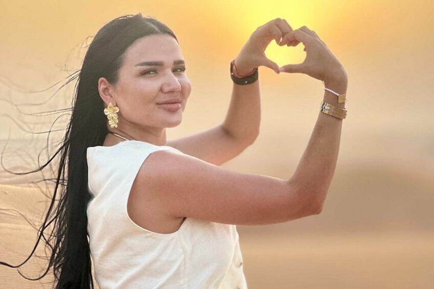 A person in a white sleeveless top making a heart shape with their hands. 3