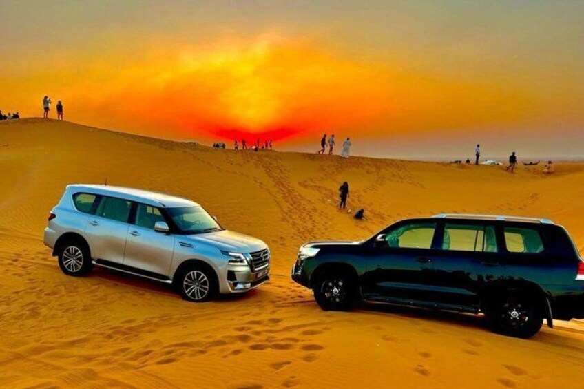 Two SUVs on a desert dune with a sunset in the background. 1