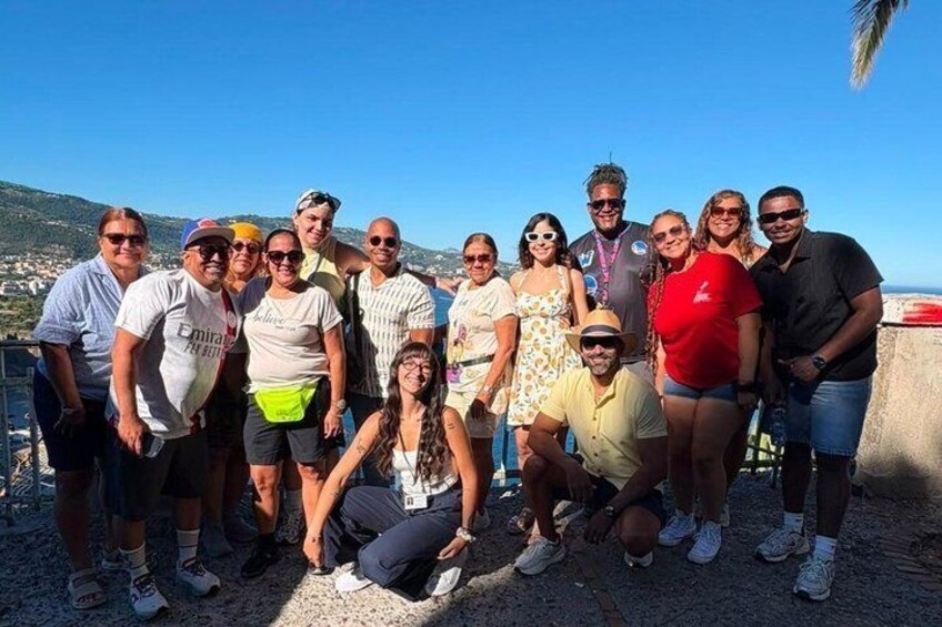 A group of people posing on a rocky seaside with a clear sky and distant hills. 4