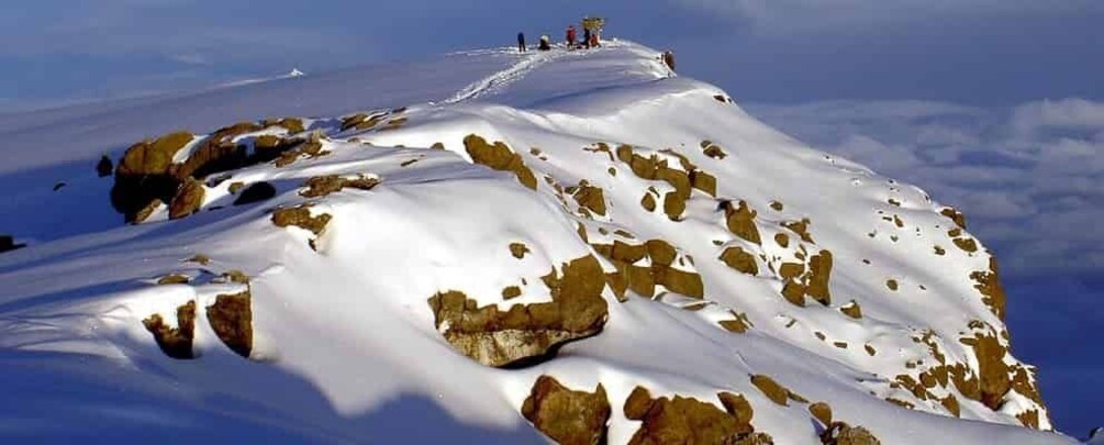 A snow-covered mountain peak with exposed rocks and a clear sky. 3