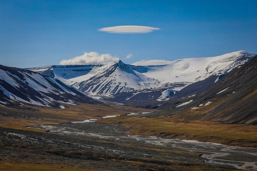 A mountainous landscape with snow-covered peaks and a valley with sparse vegetation. 3