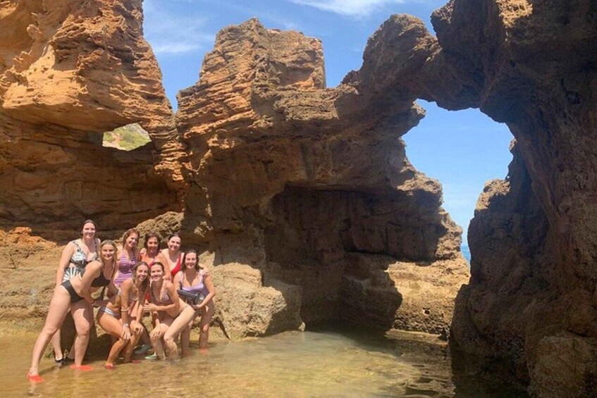 A group of people posing in a natural rock formation with a clear water pool. 4