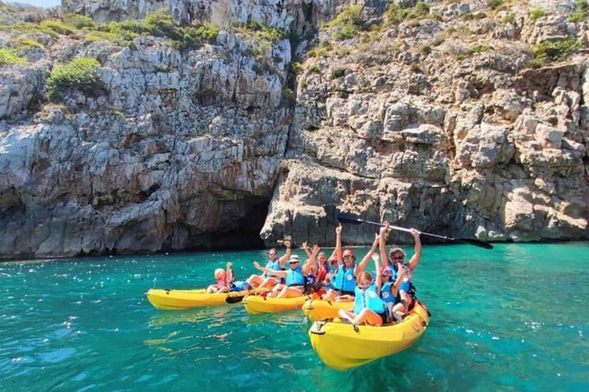 People kayaking on turquoise water with rocky cliffs in the background. 5
