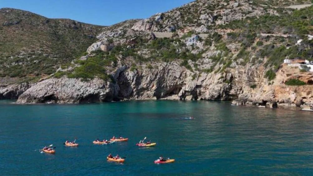A group of kayaks on a calm sea with rocky cliffs in the background. 3