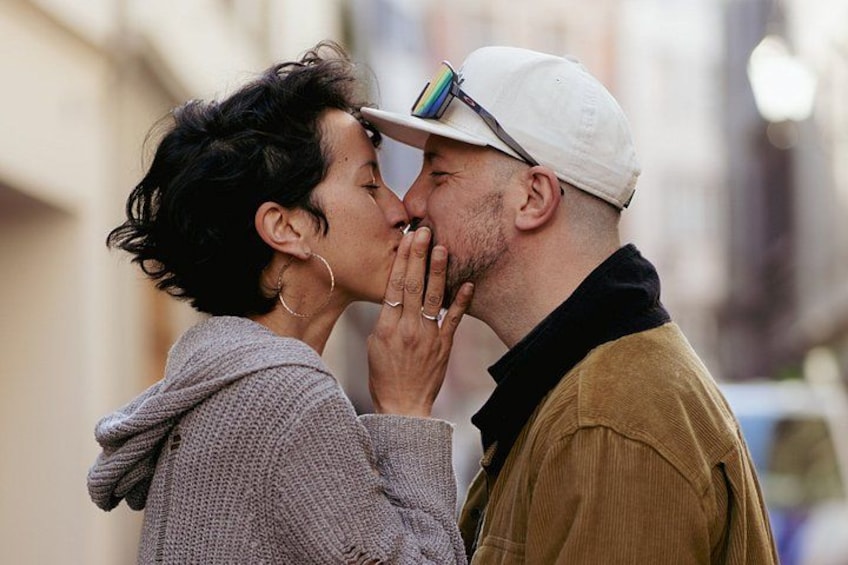 Two people embracing, one wearing a white cap and the other in a grey sweater. 1
