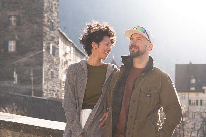 Two people standing on a ledge with a stone building in the background. 3