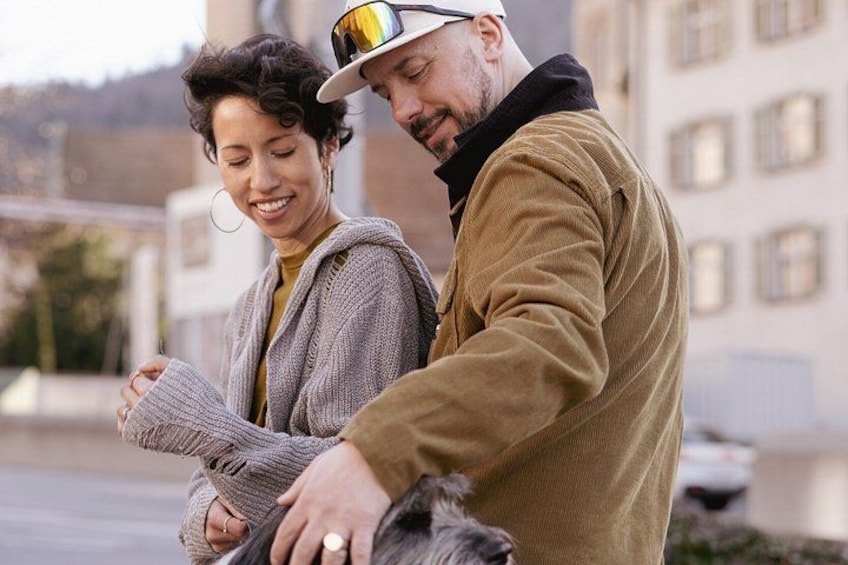 A person wearing a brown jacket and a cap, holding a dog. 4