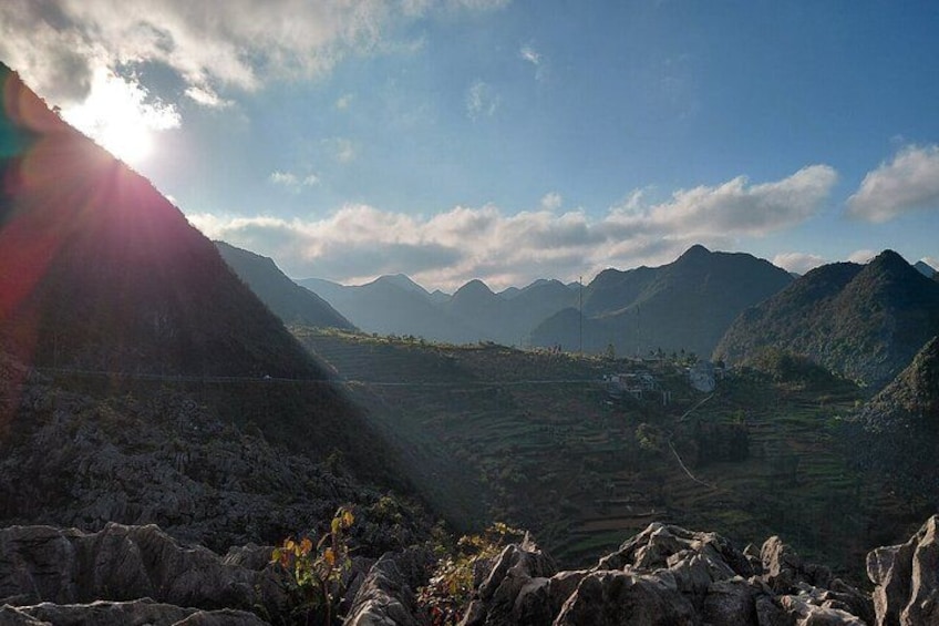 A mountainous landscape with a valley, rocky foreground, and distant mountains under a clear sky. 3
