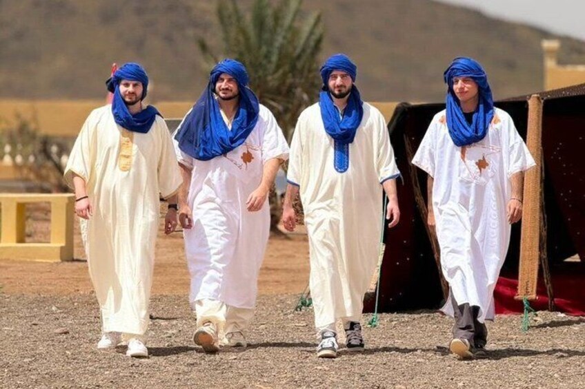 Four individuals walking on a gravel path with a desert landscape in the background. 2