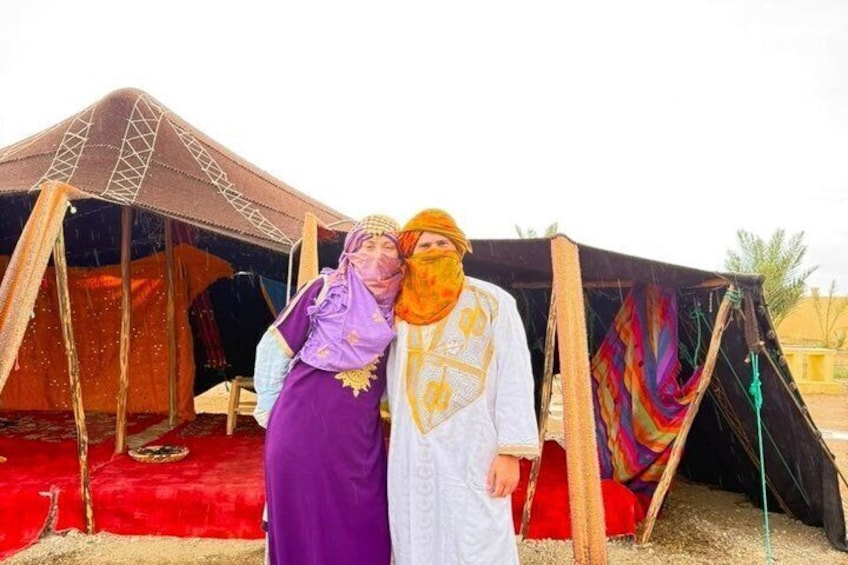 Two people standing in front of a tent with a red carpet. 5
