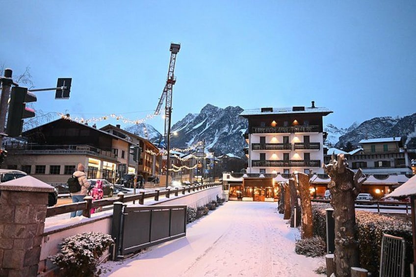 Une rue enneigée bordée d’immeubles, avec un feu de signalisation et des montagnes en arrière-plan. 5