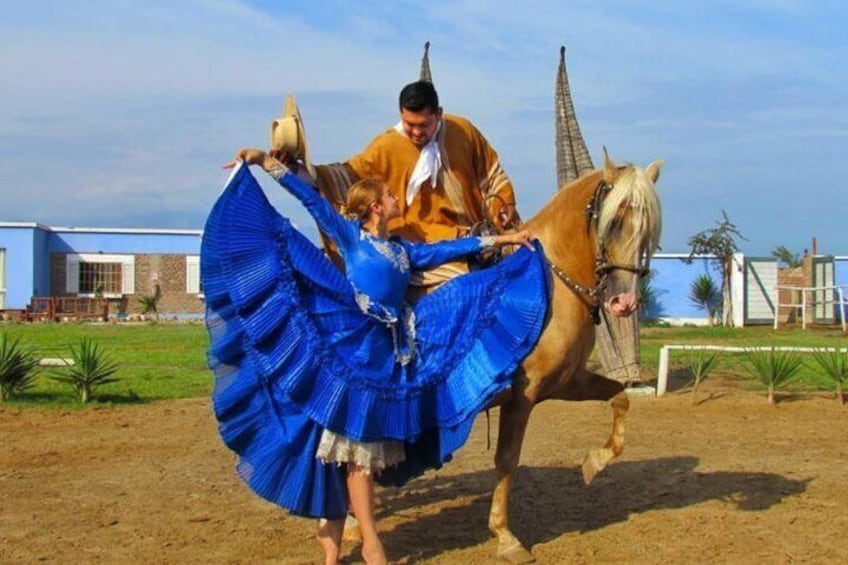 Una persona con vestido azul y un abanico, de pie junto a un caballo. 1