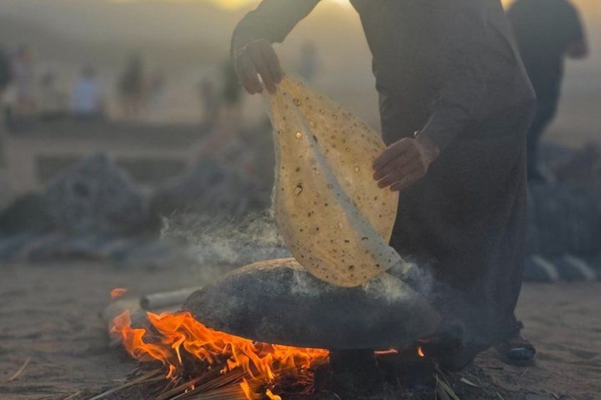 A person cooking over an open fire with a flatbread. 5