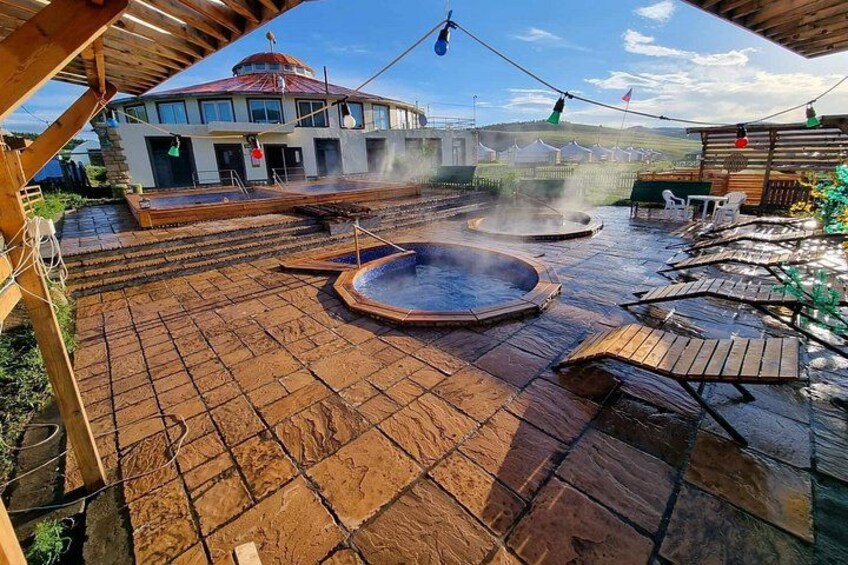 A hot spring area with wooden decking and a building in the background. 4