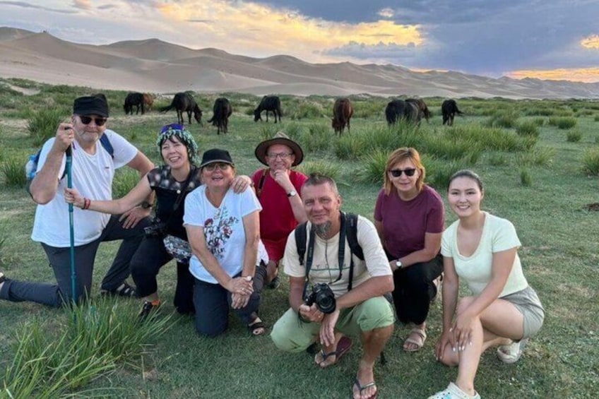 A group of people in a grassy field with mountains in the background. 1