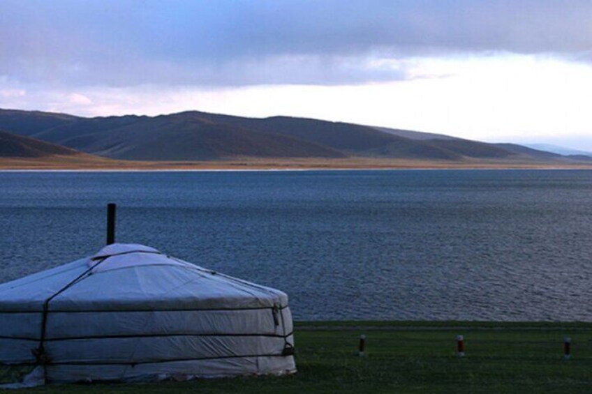 A yurt by a lake with mountains in the background. 5
