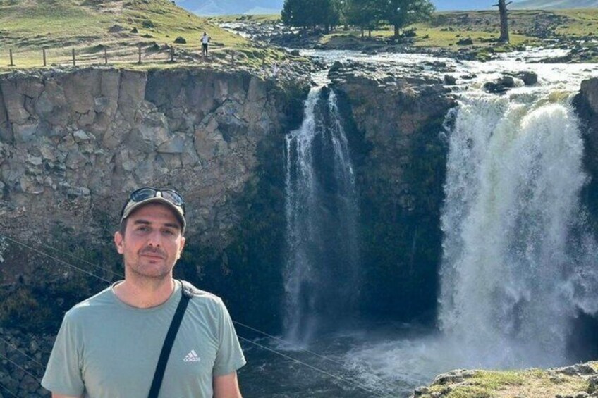 A waterfall with a person standing in front of it. 2