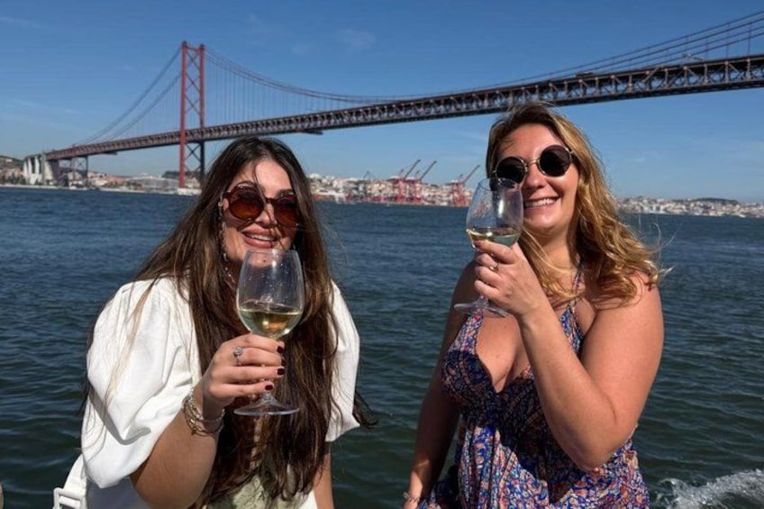 Two people holding wine glasses in front of a bridge. 2