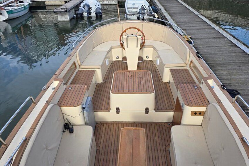 Ein Boot mit Holzboden, gepolsterten Sitzgelegenheiten und einem Steuer. 5