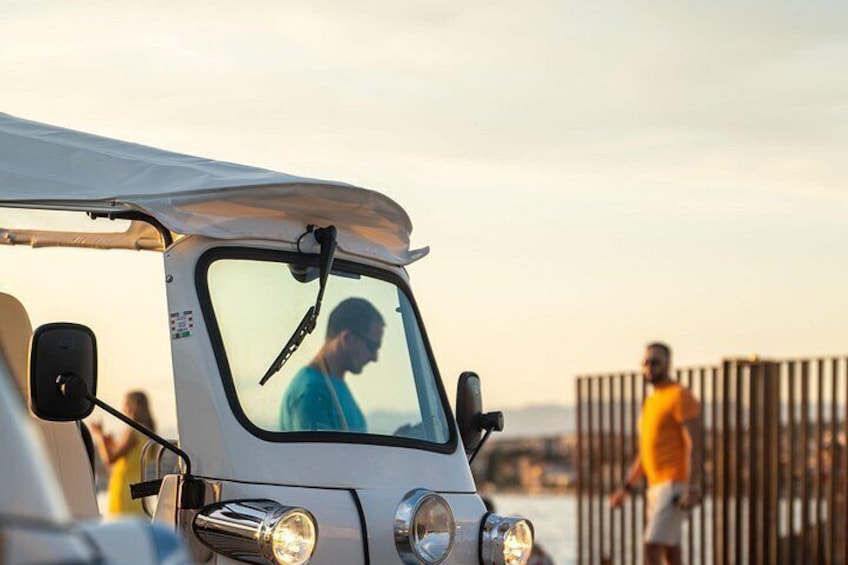 A vehicle with a white roof and a side mirror, a person inside, and a fence in the background. 4