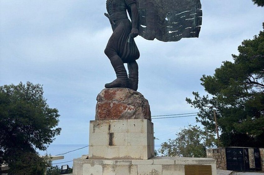 A statue of a person on a pedestal with a backdrop of trees and a clear sky. 4