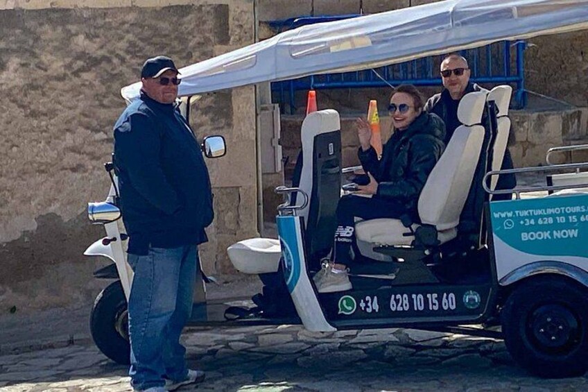 A tuk-tuk parked on a cobblestone street with a person standing beside it. 4