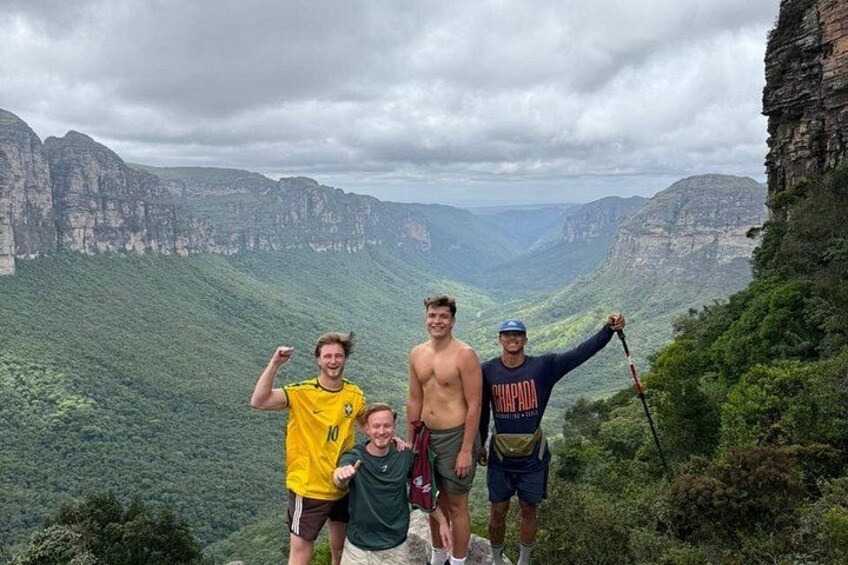 A group of people standing on a mountain ridge with a valley and cliffs in the background. 4