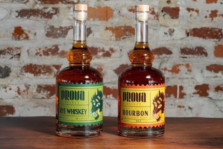 Deux bouteilles de bourbon et de whisky de seigle, posées sur une surface en bois devant un mur de briques. 2