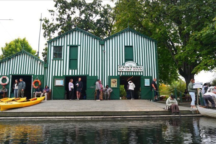 Een gebouw met groene en witte strepen en een bord waarop staat 'Punting on the Avon'. 1