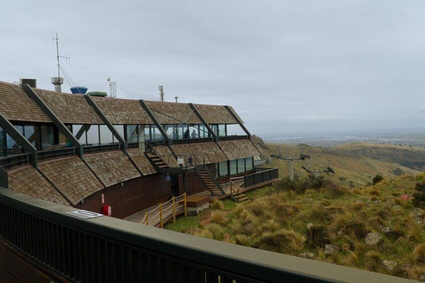 Un bâtiment moderne doté d’un toit en pente, entouré de collines verdoyantes et offrant une vue lointaine sur le paysage. 3