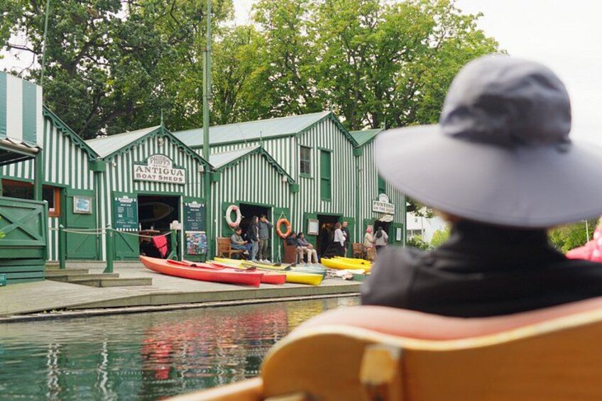 Une personne dans un bateau, un bâtiment vert portant l’inscription « Philips Antiguan Boathouse », et un canoë rouge. 2