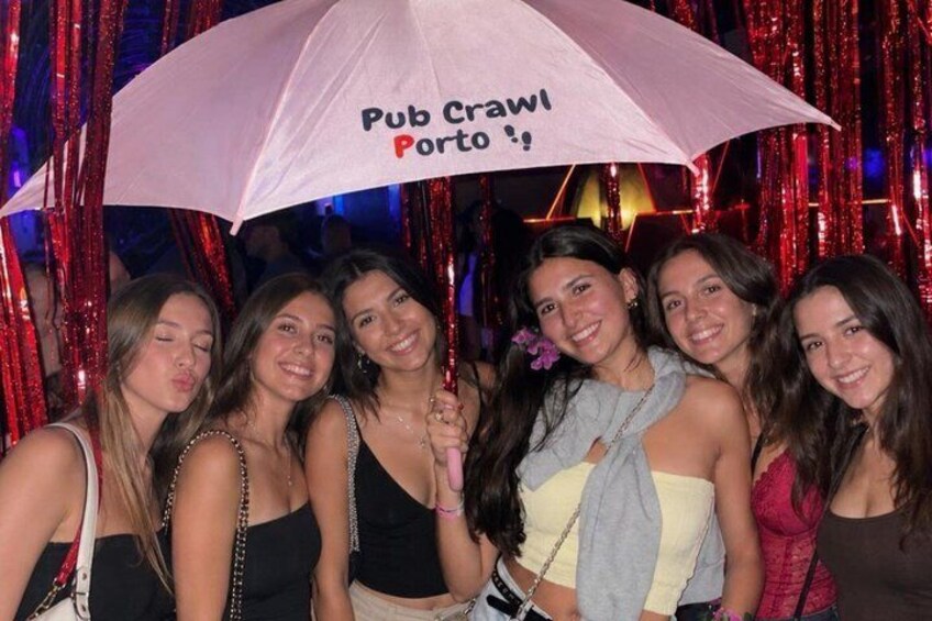 A group of people under a 'Pub Crawl Porto' umbrella. 1