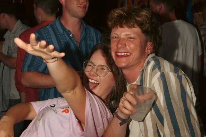 A person holding a glass, another person with a raised arm, and a crowd in the background. 3