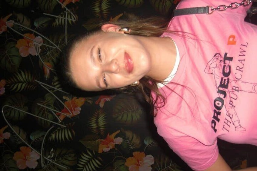 A person wearing a pink t-shirt with text and graphics, lying on a surface with a floral pattern. 4