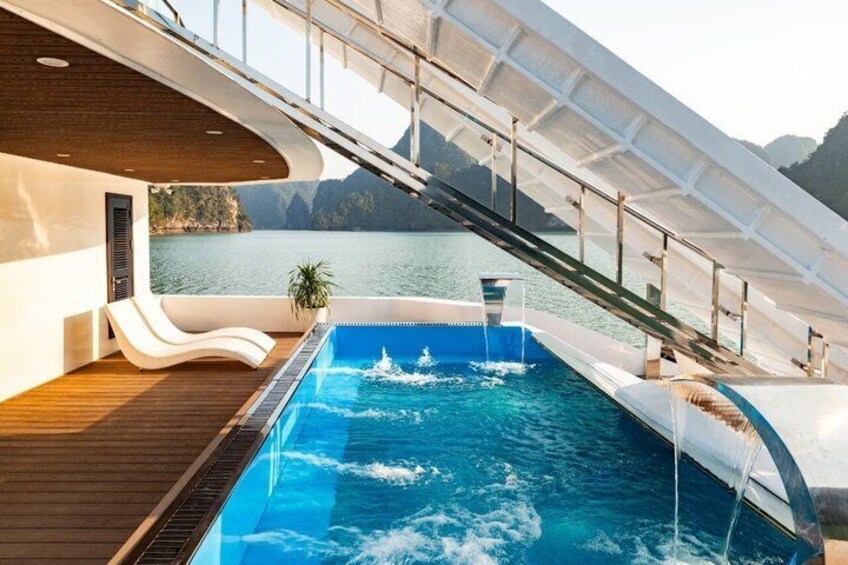 Ein Pool auf einem Boot mit einer Rutsche, umgeben von Wasser und Bergen. 4