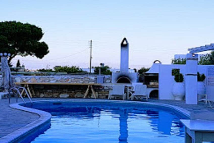 A swimming pool with white structures and a tree in the background. 2
