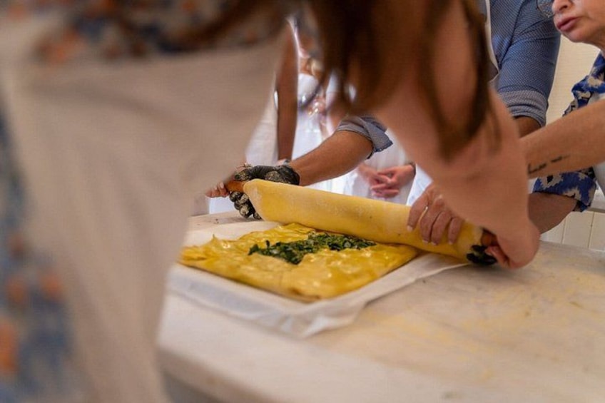 A person rolling dough with a rolling pin on a kitchen counter. 2