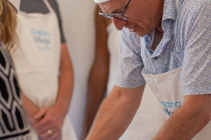 A person wearing a patterned shirt and an apron with a logo, engaged in a task. 5